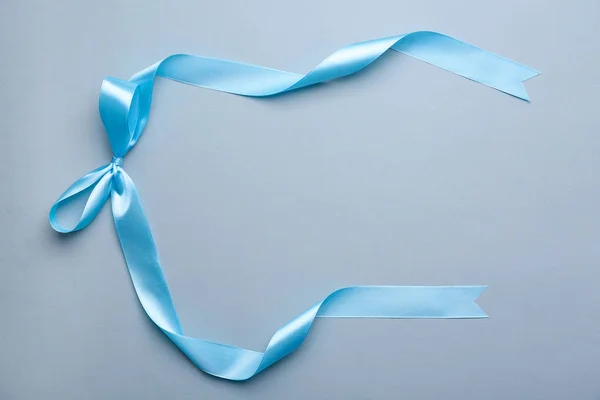 Blue ribbon with bow on color background — Stock Photo, Image