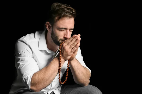 Religious young man praying to God on black background — Stock Photo, Image