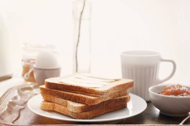 Lezzetli tost, haşlanmış yumurta, kahve ve metal tepsi üzerinde jam