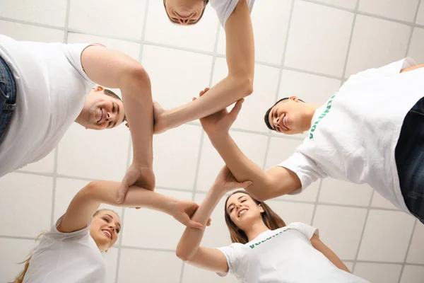 Team van jonge vrijwilligers hand in hand samen binnenshuis, onderste weergave — Stockfoto