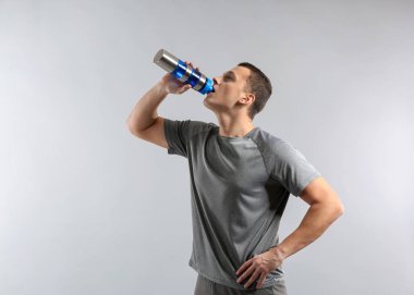 Şişe su gri arka plan ile sportif genç adam