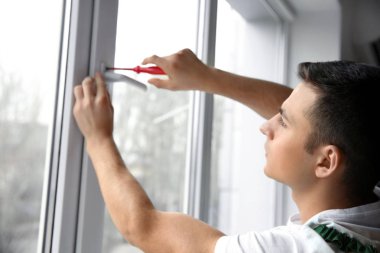 Genç bir işçi düz içinde pencere tamiri