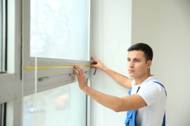 Genç bir işçi düz penceresinde ölçümleri alarak