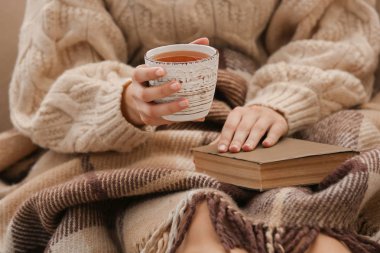 Evde, sıcak çay içme kitap portre ile genç kadın