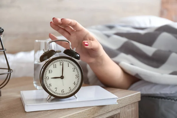 Mulher sonolenta desligando o despertador de manhã — Fotografia de Stock