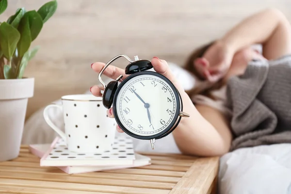 Sleepy woman turning off alarm clock in morning — Stock Photo, Image