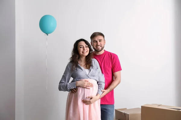 Счастливая беременная пара с вещами в новом доме — стоковое фото