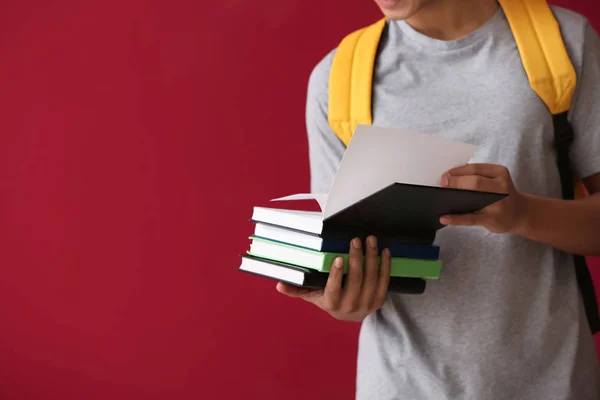 Afrikanisch-amerikanischer Schüler mit Büchern auf farbigem Hintergrund — Stockfoto