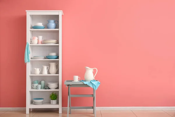 Set of clean dishes on shelves near color wall — Stock Photo, Image