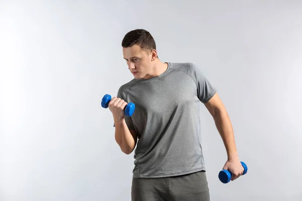 Joven deportivo entrenando con pesas sobre fondo gris —  Fotos de Stock