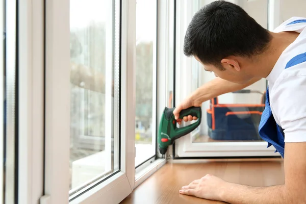 Young worker repairing window in flat — Stock Photo, Image