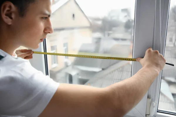 Mężczyzna robotnik pomiar okna w mieszkaniu — Zdjęcie stockowe