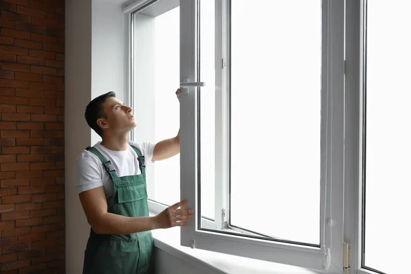 Молодой рабочий ремонтирует окна в квартире — стоковое фото