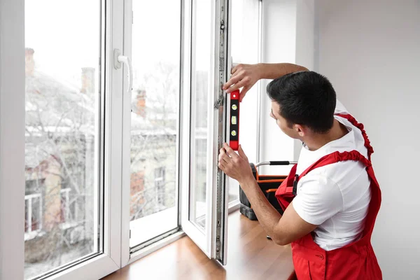 Молодий працівник встановлює вікно в квартирі — стокове фото