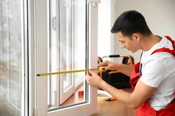 Young worker taking measurements of window in flat — Stock Photo, Image