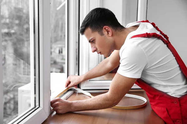 Jovem trabalhador instalando janela em plano — Fotografia de Stock