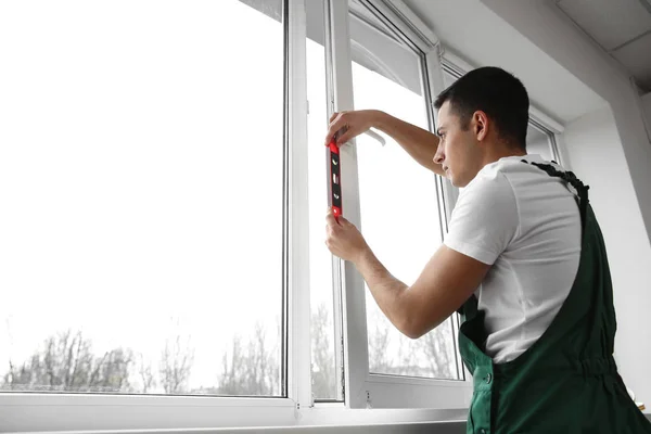 Young worker repairing window in flat — Stock Photo, Image