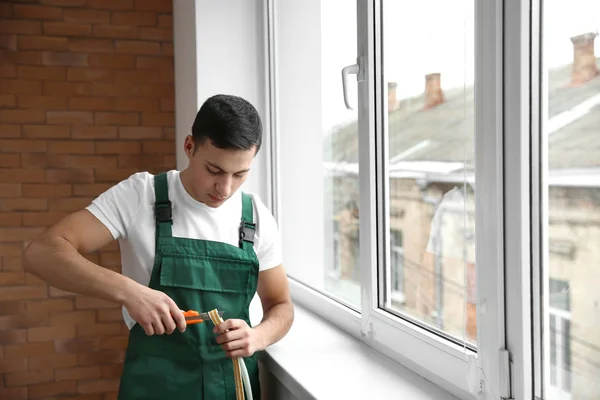 Young worker cutting seal for installation of new window — Stock Photo, Image