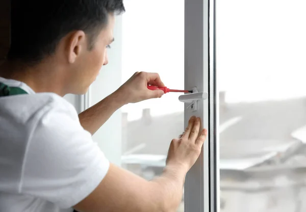 Young worker repairing window in flat — Stock Photo, Image