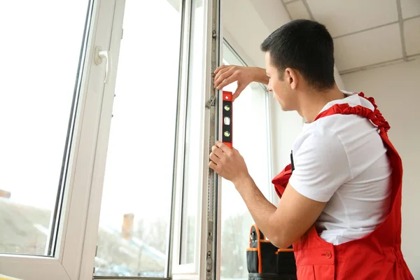 Jovem trabalhador instalando janela em plano — Fotografia de Stock