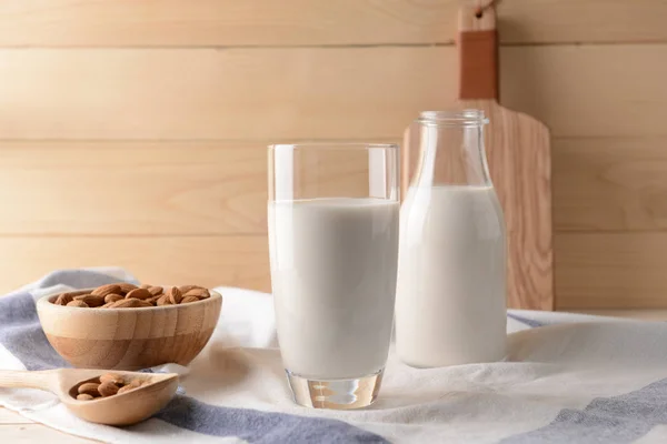 Bicchiere e bottiglia di latte di mandorla sano in tavola — Foto Stock