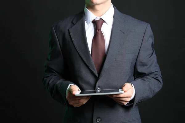暗い背景にタブレットコンピュータを持つビジネスマン — ストック写真