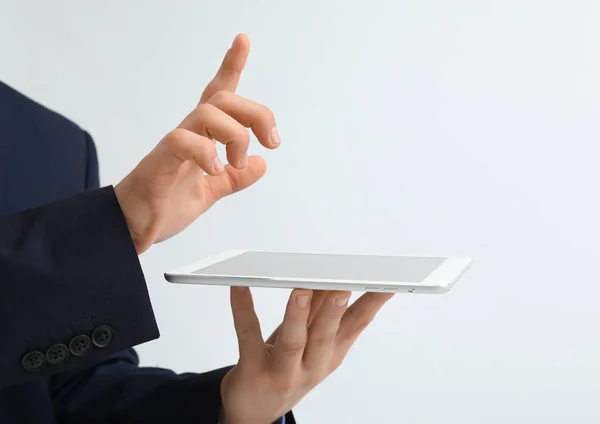 Businessman with tablet computer using virtual screen on light background — Stock Photo, Image