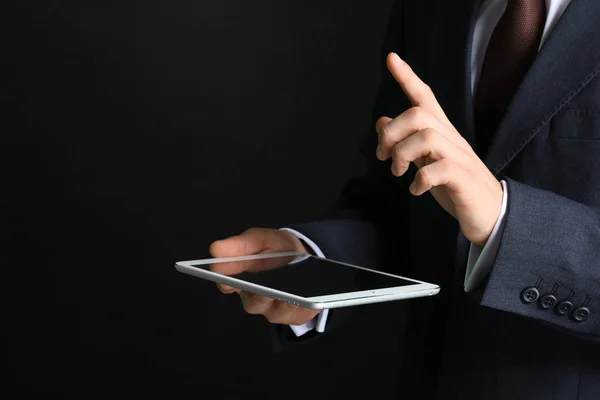 Empresario con tableta usando pantalla virtual sobre fondo oscuro — Foto de Stock