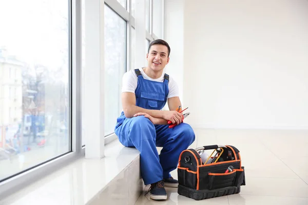 Young worker sitting on window sill in flat — Stock Photo, Image