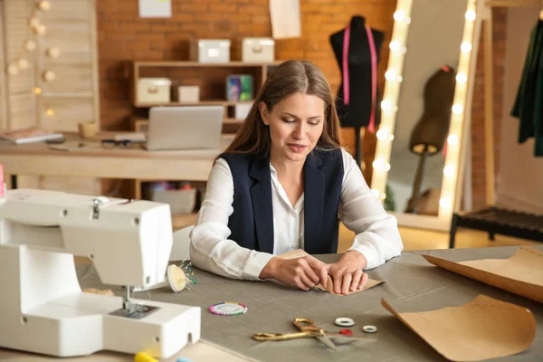 Prachtige vrouwelijke ondernemer werken met naaiende patronen in atelier — Stockfoto