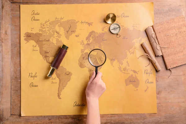 Turista donna con lente di ingrandimento che studia la mappa del mondo a tavola — Foto Stock