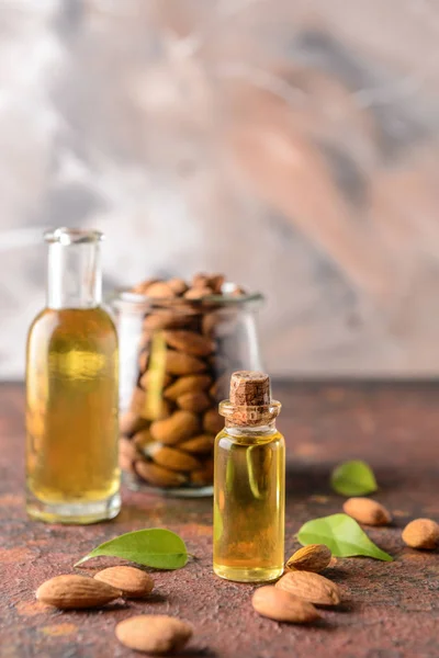 Flaschen Mandelöl und Glas mit Nüssen auf dem Tisch — Stockfoto