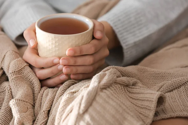 Mujer joven bebiendo té caliente en casa, primer plano — Foto de Stock