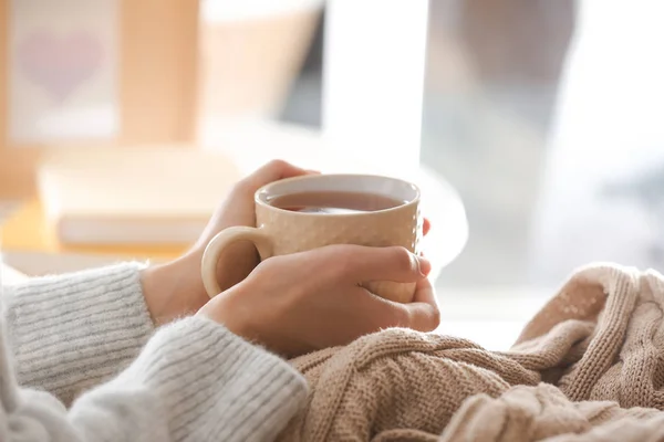 Mujer joven bebiendo té caliente en casa, primer plano — Foto de Stock