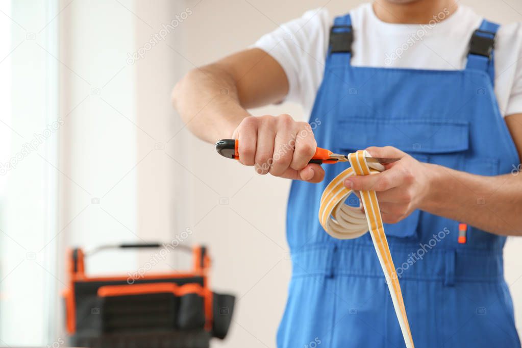 Young worker cutting seal for installation of window