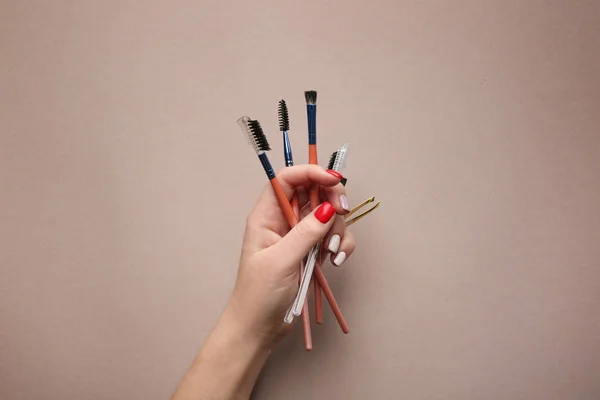 Женская рука с инструментами для коррекции бровей на цветном фоне — стоковое фото
