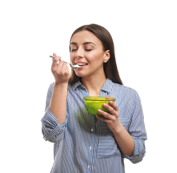 Mujer joven comiendo sabroso yogur sobre fondo blanco — Foto de Stock