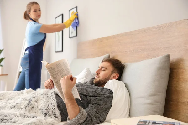 Lazy husband reading newspaper while his wife doing chores at home — Stock Photo, Image