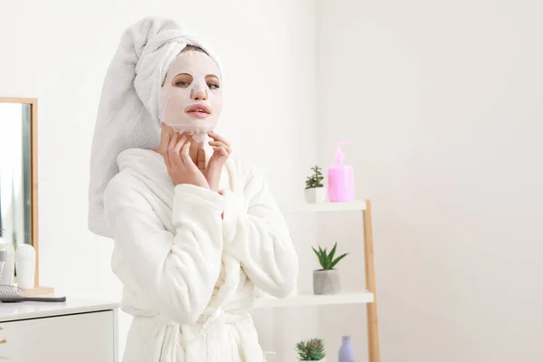 Hermosa mujer joven con mascarilla facial en casa — Foto de Stock