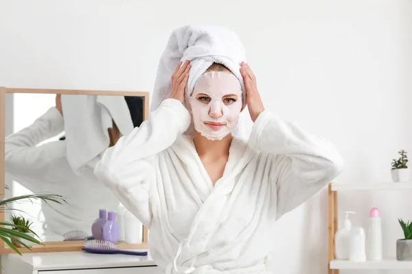 Hermosa mujer joven con mascarilla facial en casa — Foto de Stock