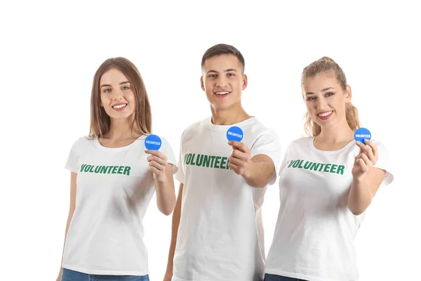 Young volunteers with badges on white background — Stock Photo, Image