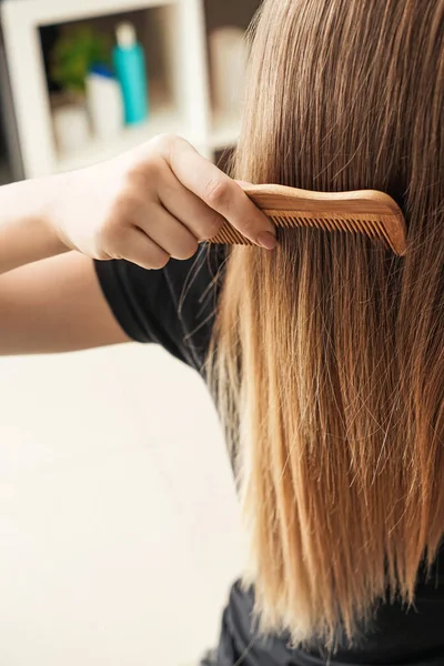 Mladá žena česání dlouhé vlasy — Stock fotografie
