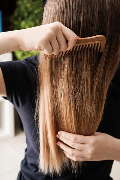 Jonge vrouw haar lange haren kammen — Stockfoto