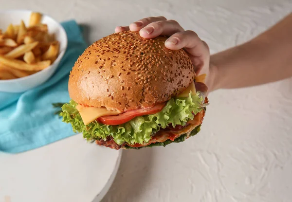 Weibliche Hand mit leckerem Burger, Nahaufnahme — Stockfoto