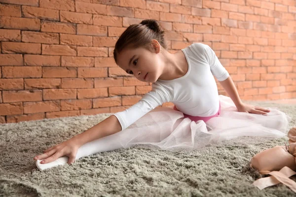 Balerina kecil yang lucu peregangan di karpet lembut — Stok Foto