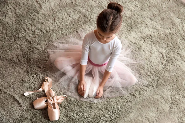 Schattige kleine ballerina zittend op zacht tapijt — Stockfoto