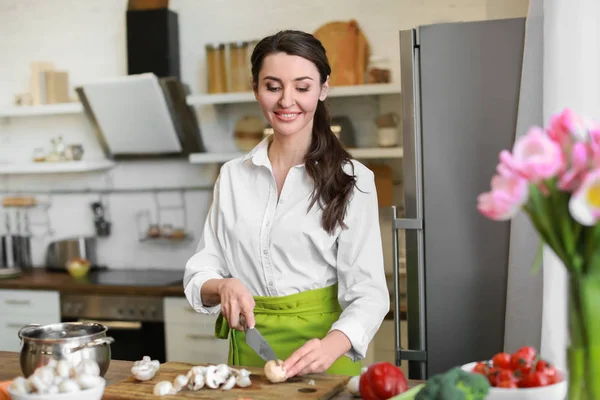 Beautiful woman cutting mushrooms in kitchen at home — Stock Photo, Image