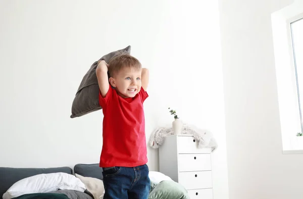 Feliz niño jugando con almohadas en la cama en casa — Foto de Stock