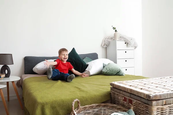 Happy little boy playing on bed at home — Stock Photo, Image