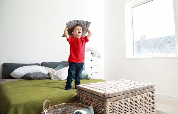 Feliz niño jugando con almohadas en la cama en casa — Foto de Stock